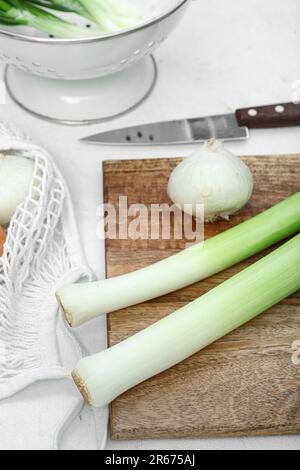 Wooden board and colander with different kinds of onion on white ...