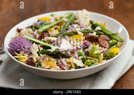 Bowl with a home made orzo salad with asparagus, fava beans and kalamata olives Stock Photo