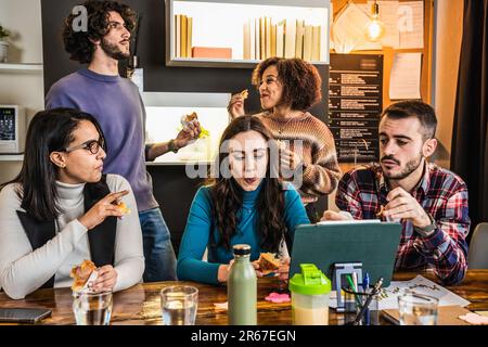 Group of young colleagues or university students using computer laptop and having fun during a break moment - Office life concept Stock Photo
