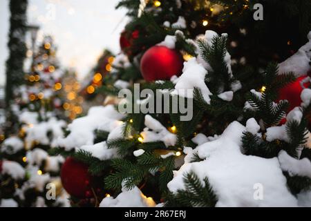 beautiful multi-colored toys on a Christmas tree against the background of lights and snow Stock Photo