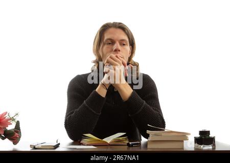 A young student sits at a table and thinks. Stock Photo