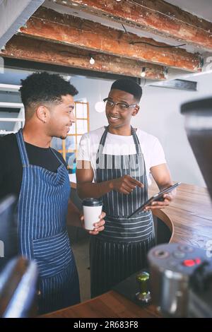 Getting orders out with good old teamwork. two young men using a digital tablet while making coffee at a cafe. Stock Photo
