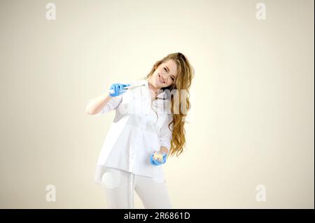 Photopolymer lamp Doctor Fairy with a glowing blue lamp in a white medical suit Dentist treatment of teeth prosthetics put fillings treat gums caries beautiful woman on white background studio ad Stock Photo