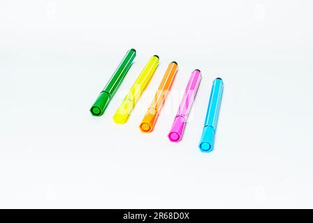 A row of four vibrant colored pens placed neatly on a table surface Stock Photo