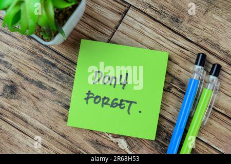 Concept of Don't Forget write on sticky notes isolated on Wooden Table. Stock Photo