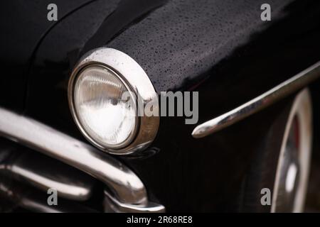 Izmir, Turkey - June 3, 2023: Close-up shot of the headlight on a black 1950 Plymouth at the IZKOD Classic Car Meet at Buca Pond Stock Photo