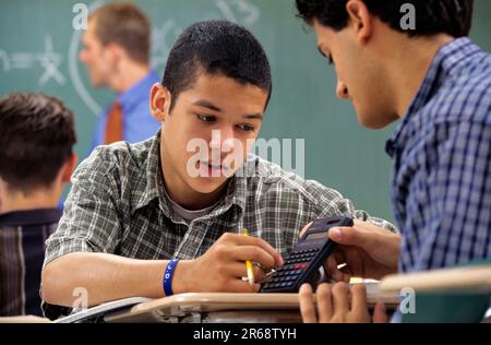 two students work with a calculator on a project in math class Stock Photo