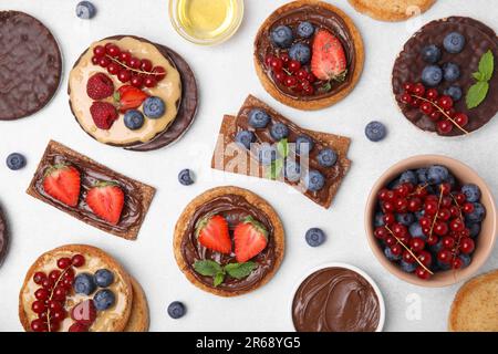 Fresh rye crispbreads, crunchy rice cakes and rusks with different toppings on light grey table, flat lay Stock Photo