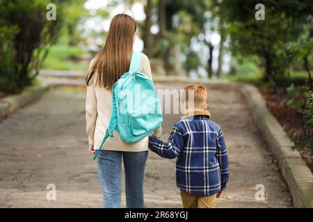 Young mom taking her son to school, back view Stock Photo