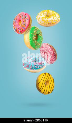 Sweet tasty donuts falling on light blue background Stock Photo