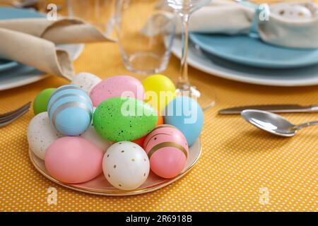 Festive table setting with painted eggs, glasses and cutlery. Easter celebration Stock Photo