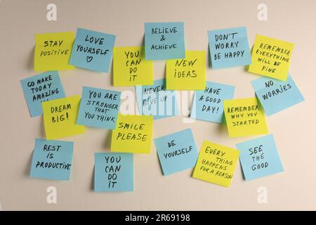 Paper notes with life-affirming phrases on white wall Stock Photo