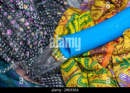 Water flows through the hose into the washing machine, preparing to rinse the laundry, close up Stock Photo