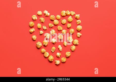 Heart made of crispy popcorn on red background Stock Photo