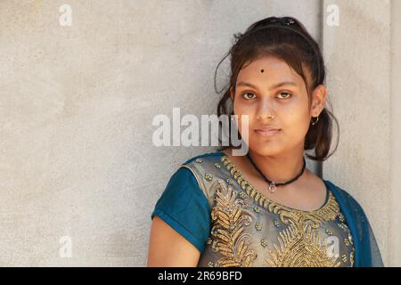 Portrait of a beautiful young teenage girl, Indian nationality. Against the background of the textural wall with copy space for text or word. Outdoors Stock Photo