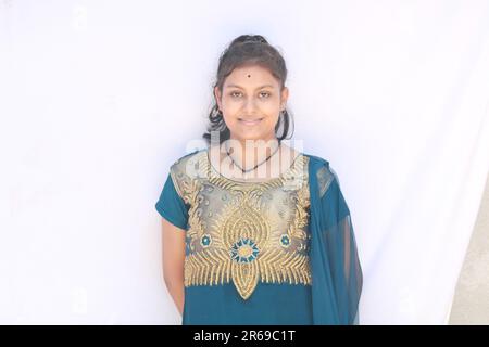 Portrait of a smiling Asian Indian Girl standing and looking at camera isolated over white background. Stock Photo
