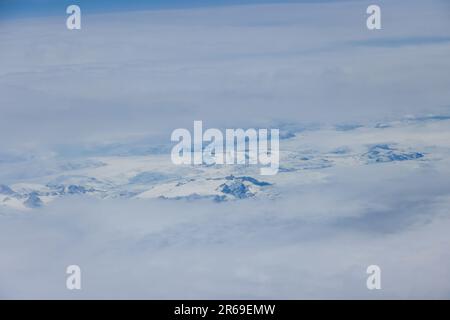 Greenland mountain peaks with their lofty heights and snowy slopes create striking landscape enveloped in clouds Stock Photo