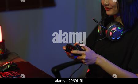 Female cyber hacker gamer using controller joystick to playing or streaming games on computer. Stock Photo
