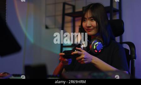 Female cyber hacker gamer using controller joystick to playing or streaming games on computer. Stock Photo