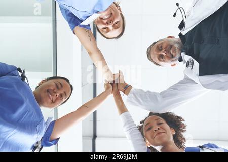 Modern day miracle workers unite. Low angle portrait of a diverse group of healthcare professionals standing and giving each other a high five. Stock Photo