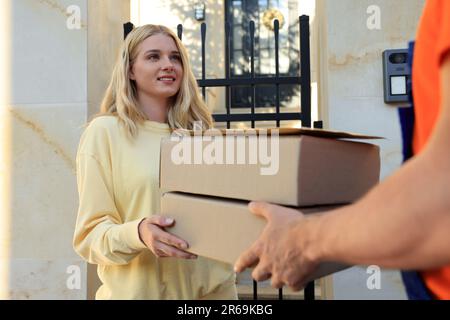 Young woman receiving parcels from courier outdoors Stock Photo