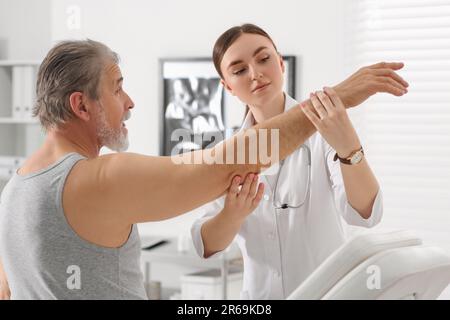 Female orthopedist examining patient's arm in clinic Stock Photo