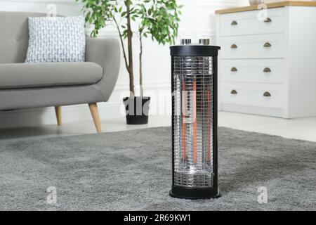 Modern infrared heater on carpet in cozy room Stock Photo