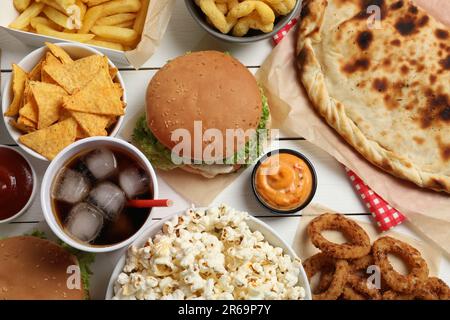 Burgers, chips and other fast food on white wooden table, flat lay Stock Photo