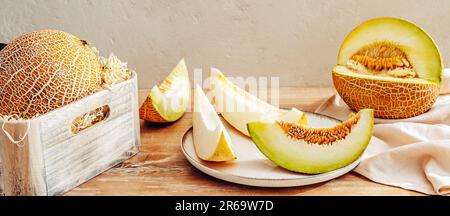 Various sliced melons on wooden table by stone wall Stock Photo