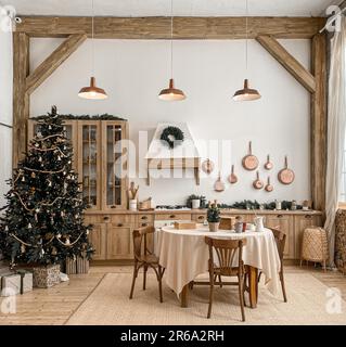 Modern, light, festive, cozy kitchen interior with Christmas and New Year decorations, kitchen table, utensils, copper pans on wall and big Christmas Stock Photo