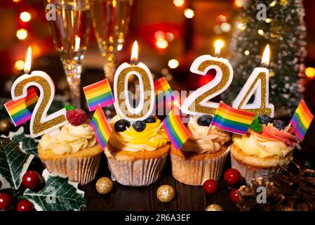 Food tray with cupcakes new year candles wineglasses and rainbow flags decorations Stock Photo