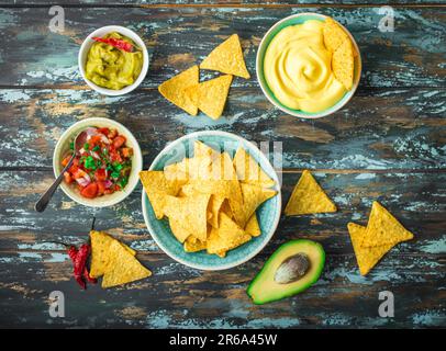 Mexican tortilla chips with guacamole, cheese, salsa dips. Nachos and assorted dips. Mexican party food, appetizers. Top view. Tortilla chips Stock Photo