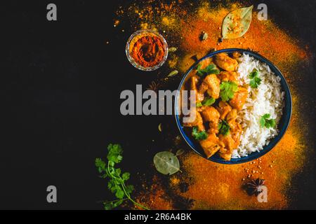 Indian Butter chicken with basmati rice in bowl, spices, black background. Space for text. Butter chicken, traditional Indian dish. Top view. Chicken Stock Photo