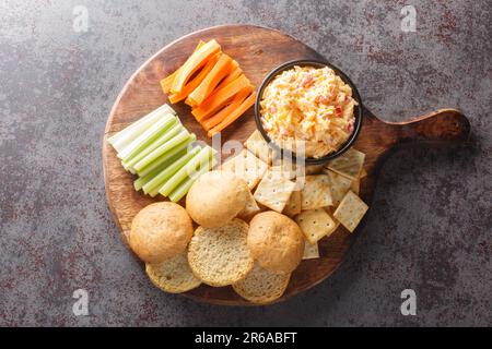 Pimento or pimiento cheese is a spread made of cheese, mayonnaise and pimientos and served on crackers and vegetables closeup on the wooden board on t Stock Photo
