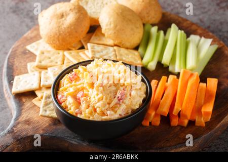 Pimento cheese with celery, carrot sticks and crackers closeup on the wooden board on the table. Horizontal Stock Photo