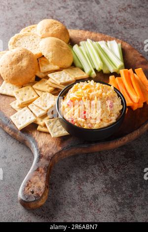 Homemade Pimento Cheese Spread with Crackers and Veggies closeup on the wooden board on the table. Vertical Stock Photo