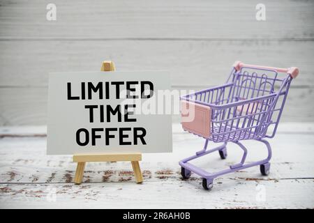 Limited Time Offer text message and trolley shopping cart on wooden background Stock Photo