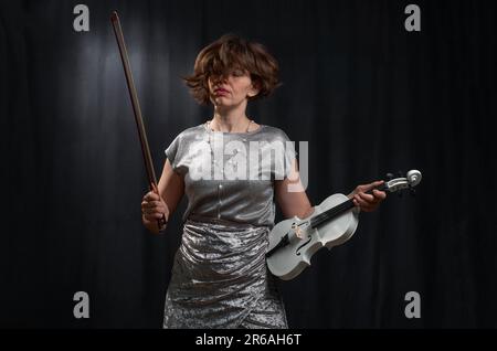 Half-length portrait of a woman playing the violin on a black background Stock Photo