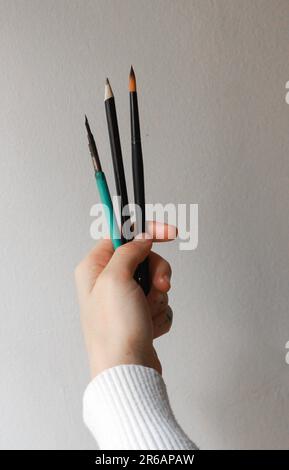 Woman's hands holding brushes. Concept of a person thinking about his next piece of art. Concept of painting and creative process. Stock Photo