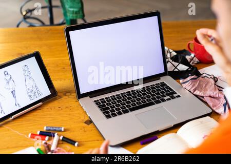 Close up of biracial transgender fashion designer using tablet and laptop with copy space on screen Stock Photo