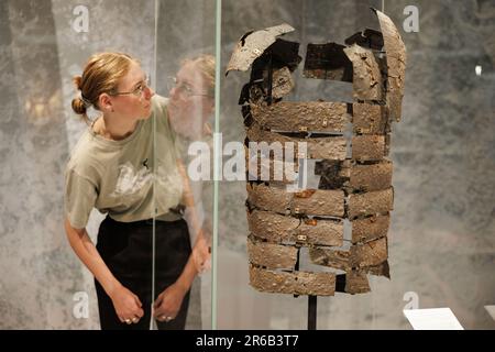 Bramsche, Germany. 08th June, 2023. Exhibition assistant Lea Engel looks at a Roman rail tank (9 AD). In 2018, the Varus Battle Museum in Kalkriese found a Roman rail tank during excavations - according to the museum, the oldest so far and the only one preserved worldwide. The museum is showing further exhibits on this in the special exhibition 'Cold Case - Death of a Legionnaire' from June 10 to Nov. 5, 2023. Credit: Friso Gentsch/dpa/Alamy Live News Stock Photo