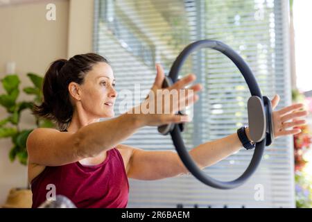 Focused caucasian female coach using exercise ring in pilates class Stock Photo