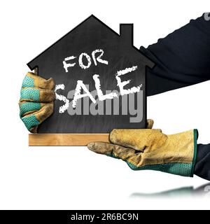 Hands with protective work gloves, holding a blackboard in the shape of a small house with text For Sale. Isolated on white background with copy space Stock Photo