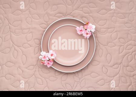 Empty beige plate on a light cream color fabric tablecloth. Table top view. Serving utensil. Modern trendy ceramic tableware. Crockery. Menu template Stock Photo
