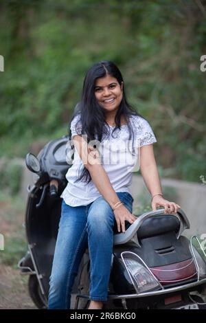 An Indian beautiful young girl with scooter smiling and having fun Stock Photo