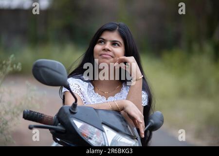 An Indian beautiful young girl with scooter smiling and having fun Stock Photo