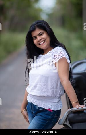 An Indian beautiful young girl with scooter smiling and having fun Stock Photo