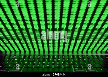 Half-closed computer screen showing rows of glowing binary numbers reflected on laptop keyboard. Illustration of the Internet and computer world Stock Photo