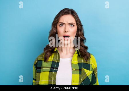 Photo of shocked crazy offended woman with curly hairdo dressed checkered shirt staring open mouth isolated on blue color background Stock Photo