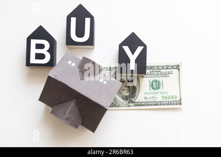 Houses, money bag with dollar sign on wooden cubes with word buy. Concept of mortgage and real estate buying Stock Photo